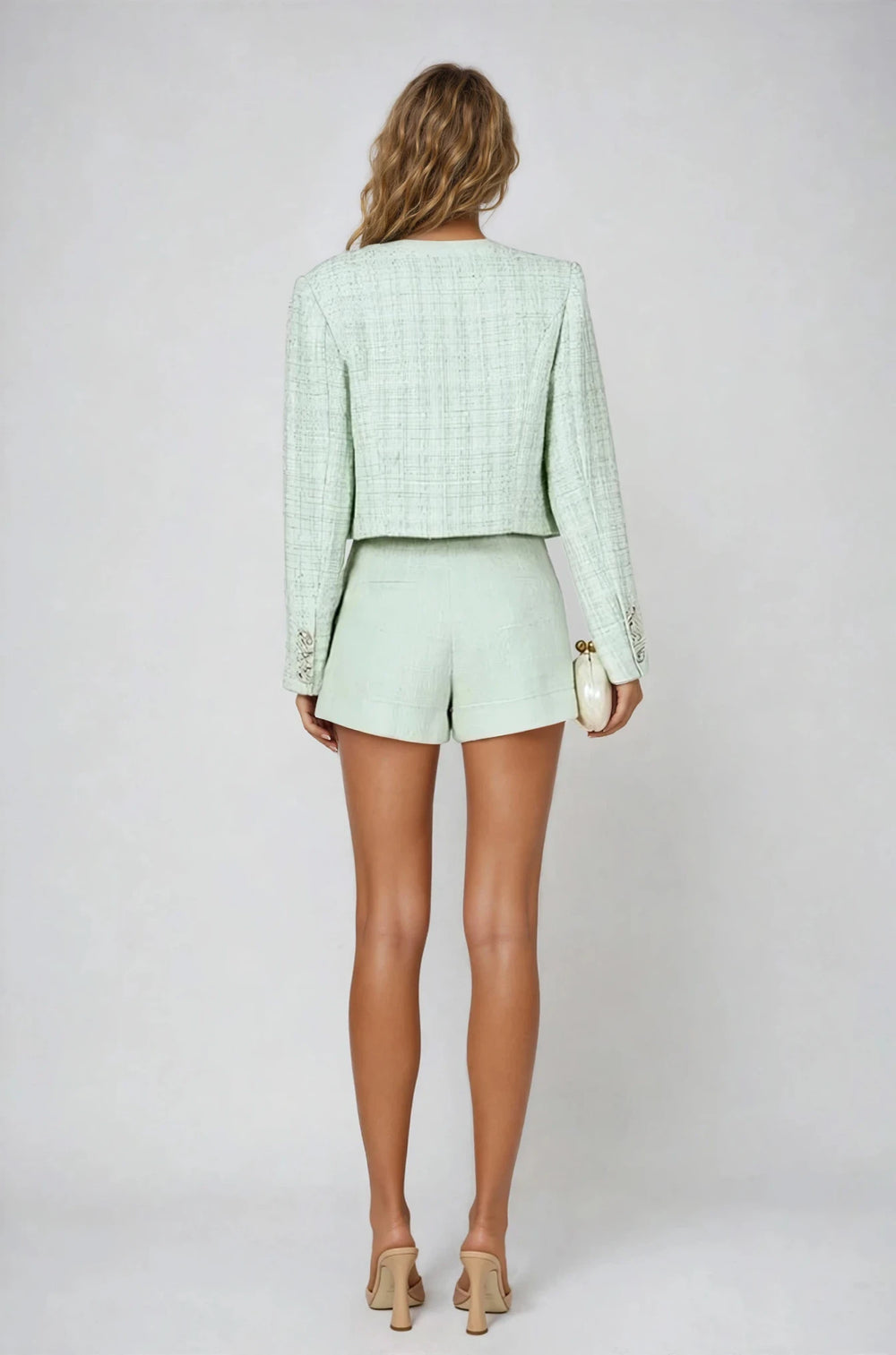 Woman wearing a light green outfit with shorts and a jacket on a white background