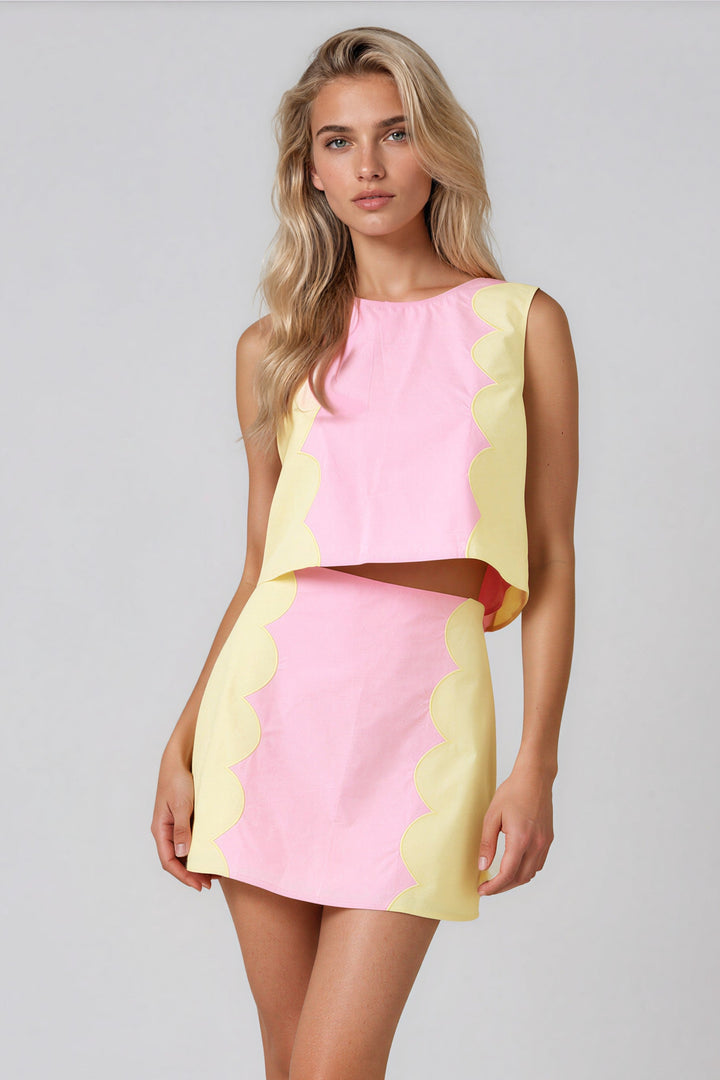 Woman wearing pink and yellow scalloped color block top and A-line mini skirt set