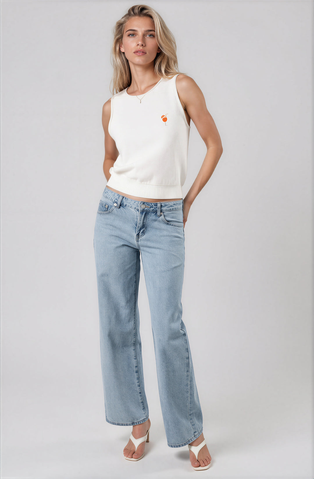 white sleeveless sweater top with embroidered spritz detail