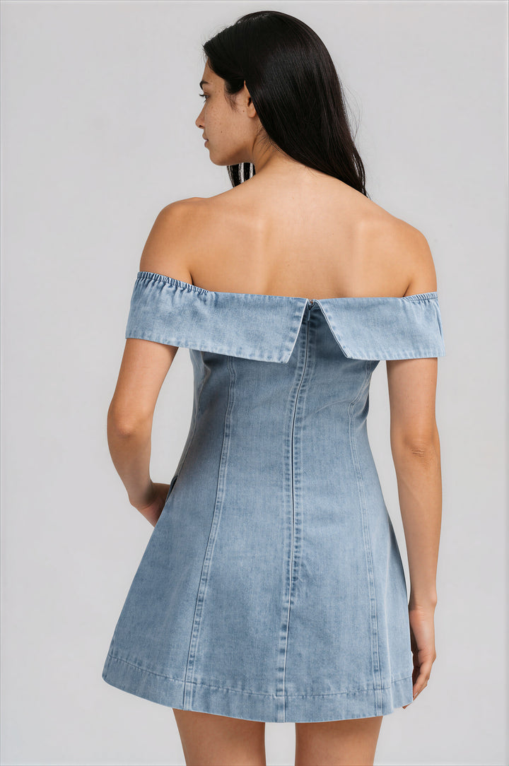 Woman wearing a denim off-shoulder dress against a gray background