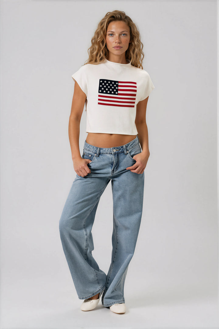 Woman wearing a white t-shirt with an American flag design and blue jeans on a beige background