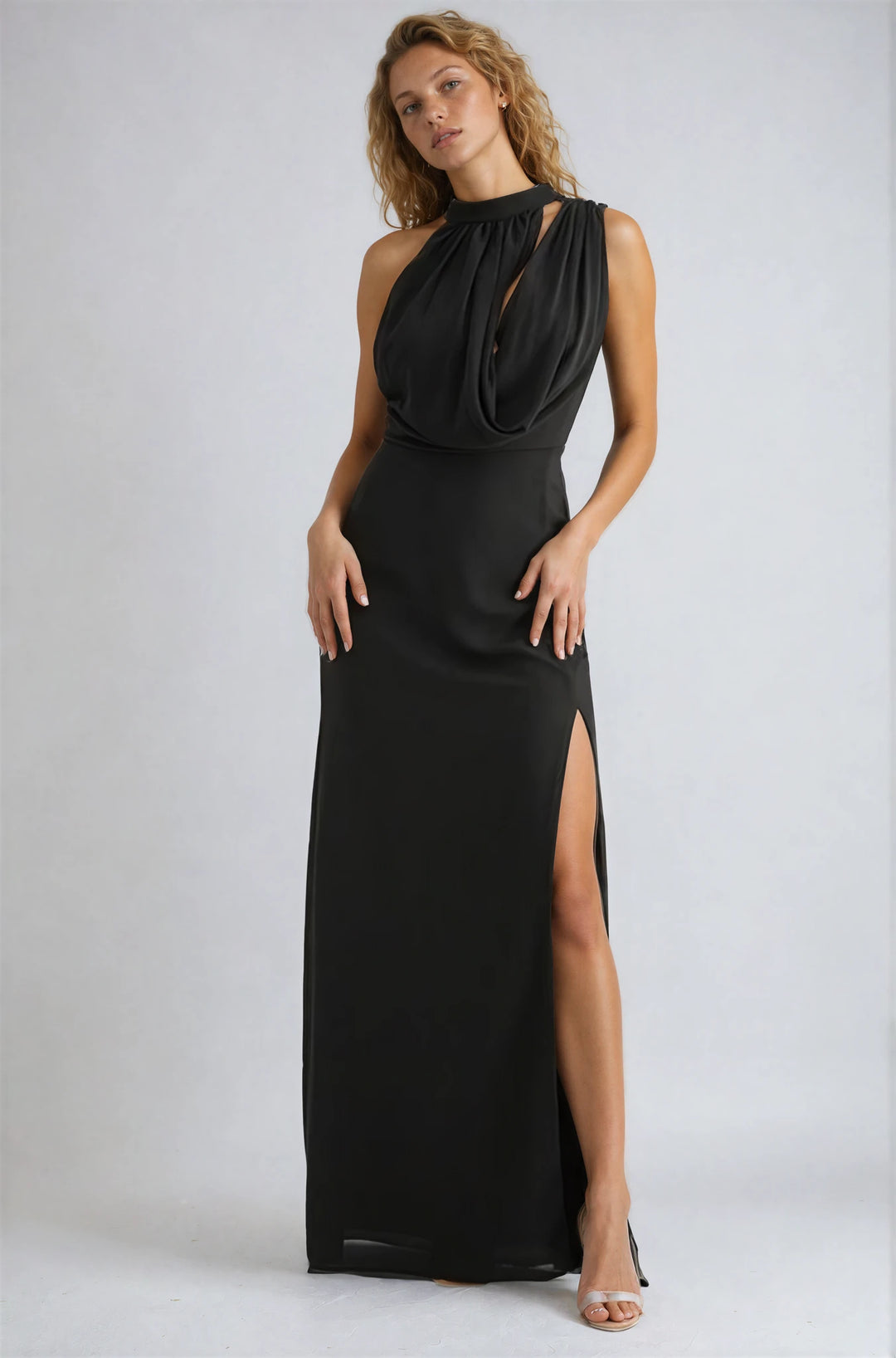 Woman wearing a black evening gown with a slit on a white background