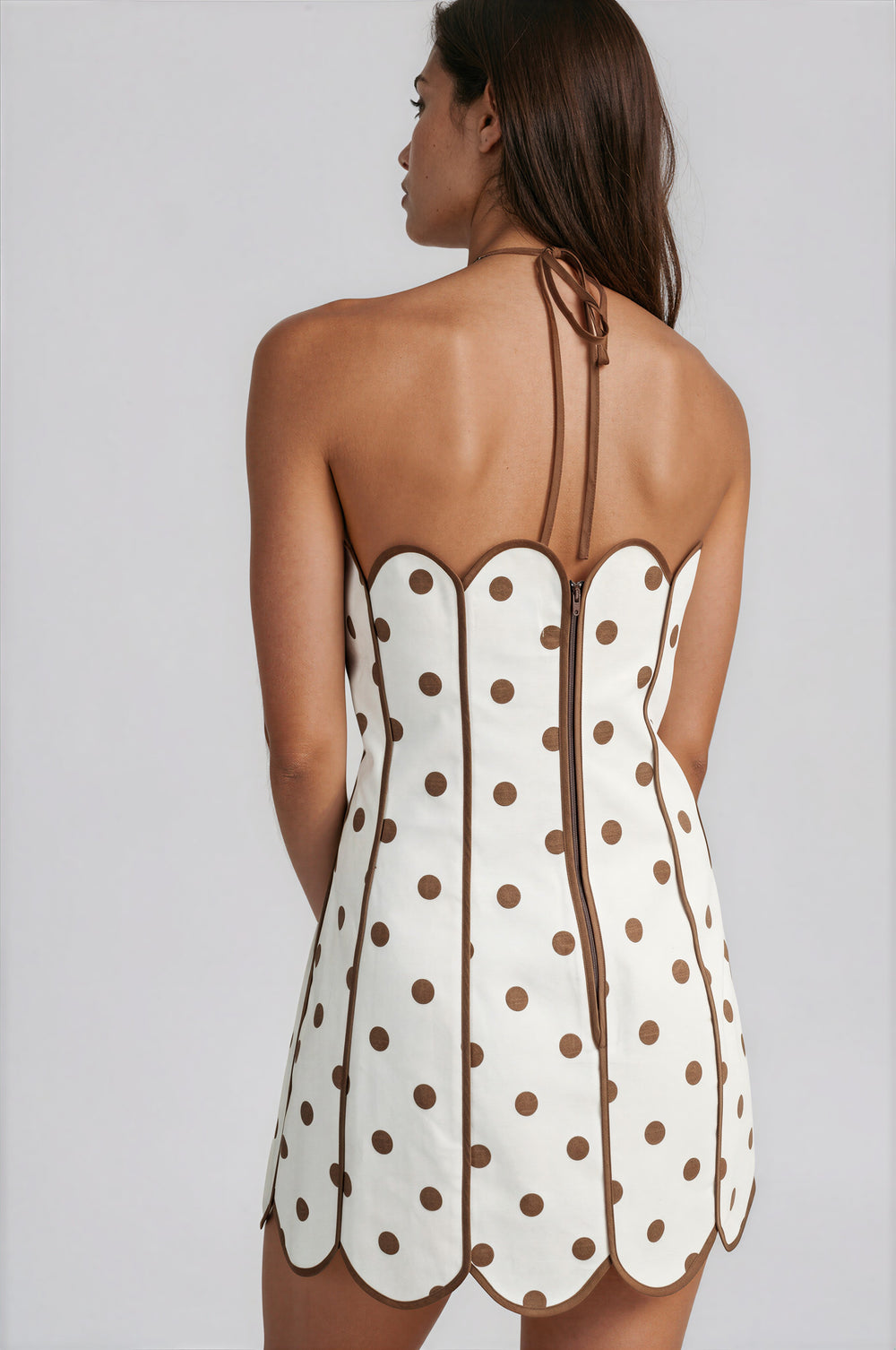 White dress with brown polka dots and thin straps on a gray background