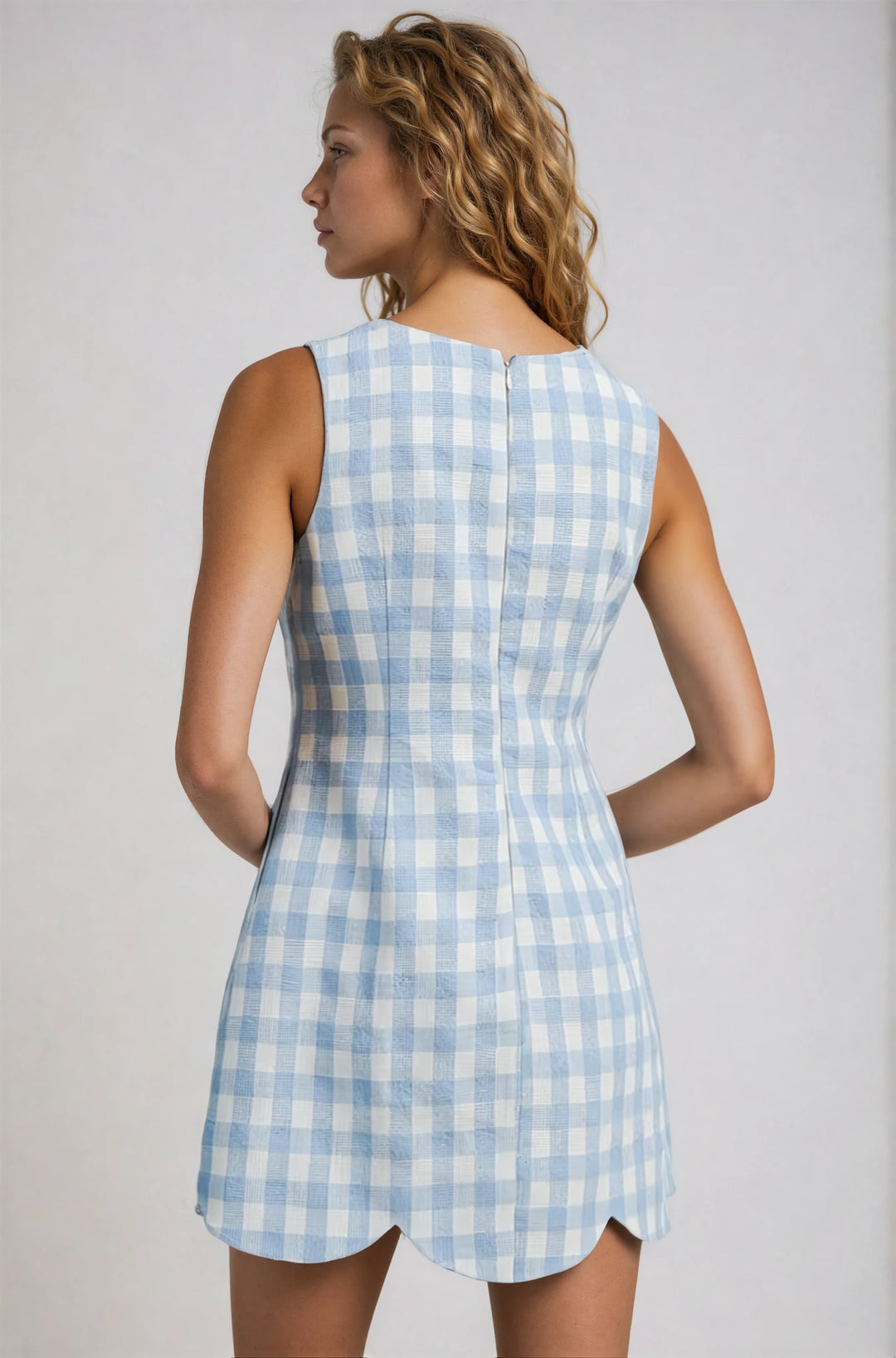 Woman wearing a blue and white checkered dress against a plain background