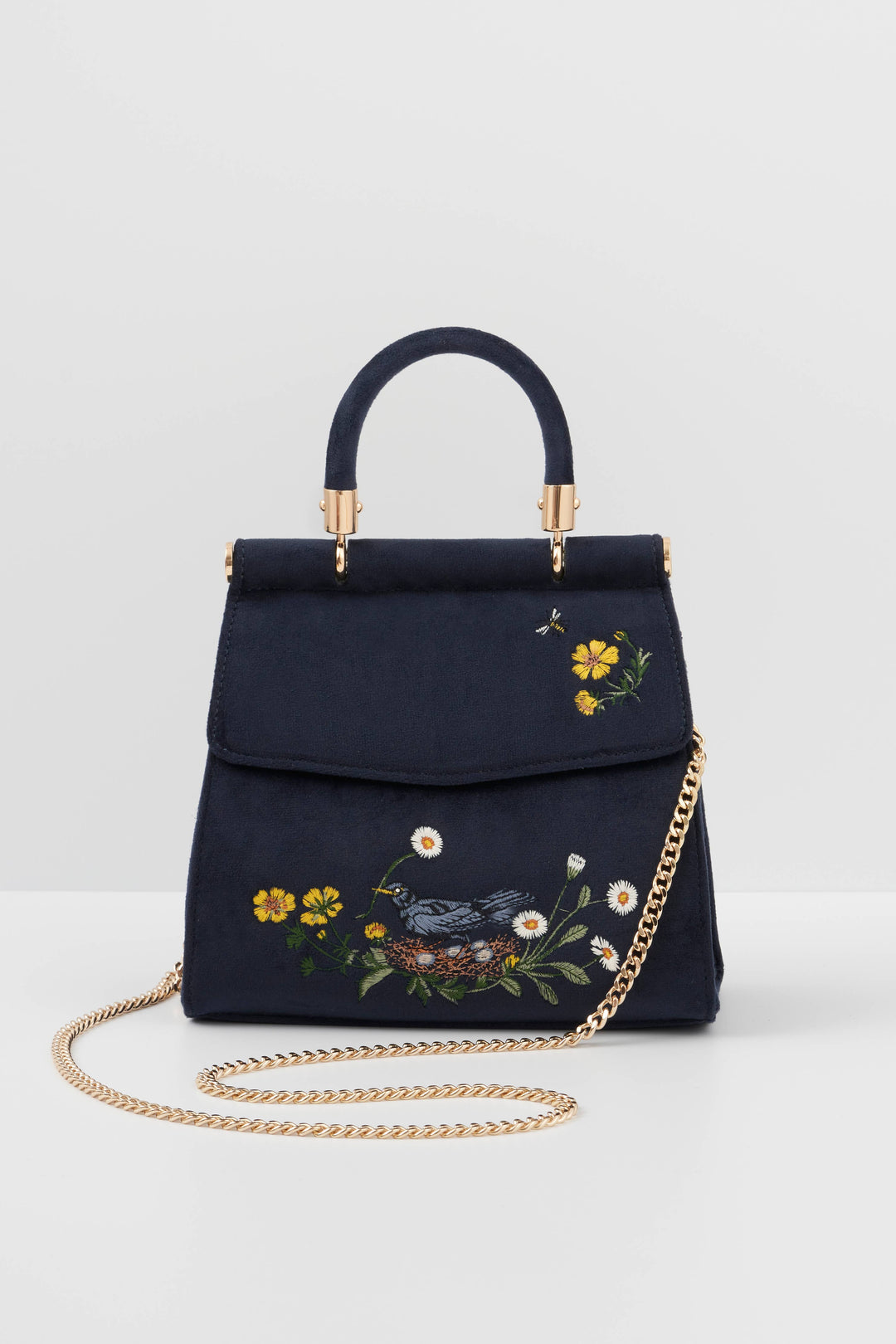 Navy blue handbag with floral embroidery and gold chain on a light gray background