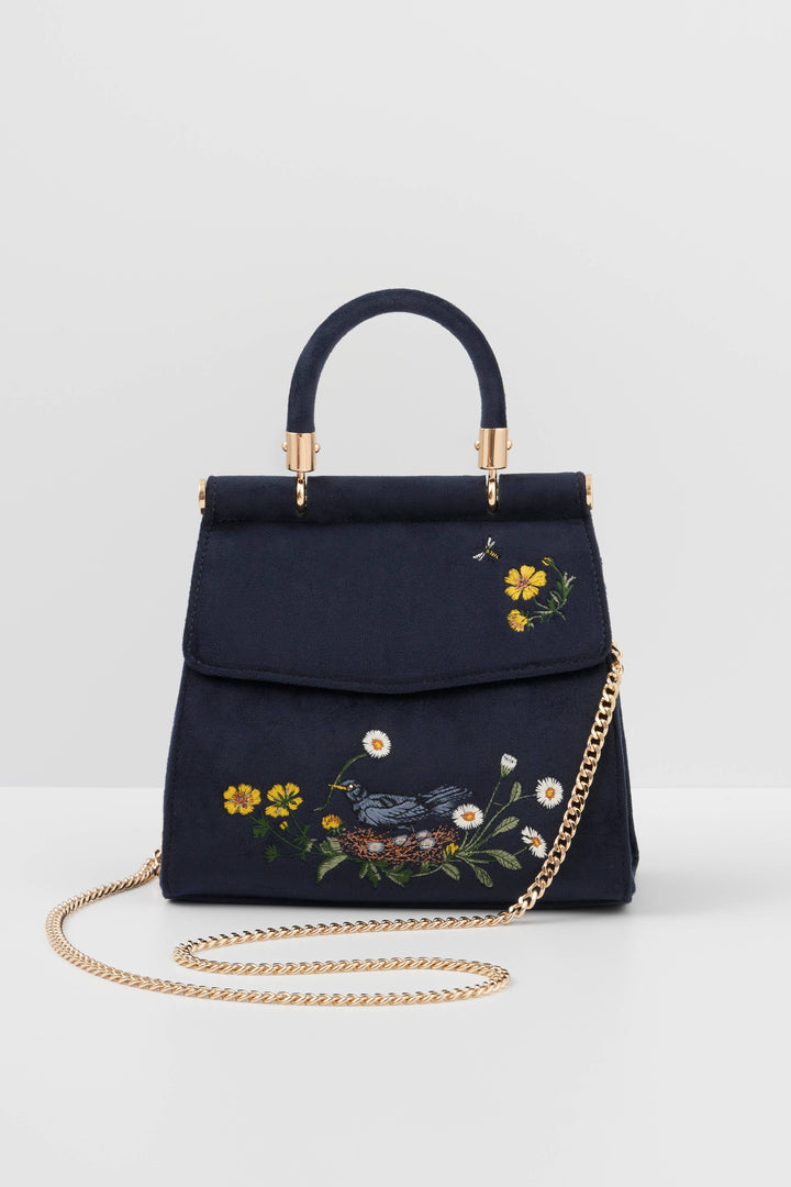 Navy blue handbag with floral embroidery and gold chain on a light gray background