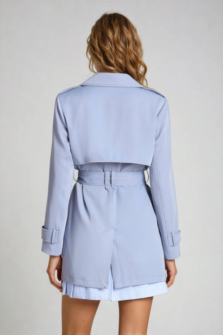 Light blue trench coat worn by a person on a plain background