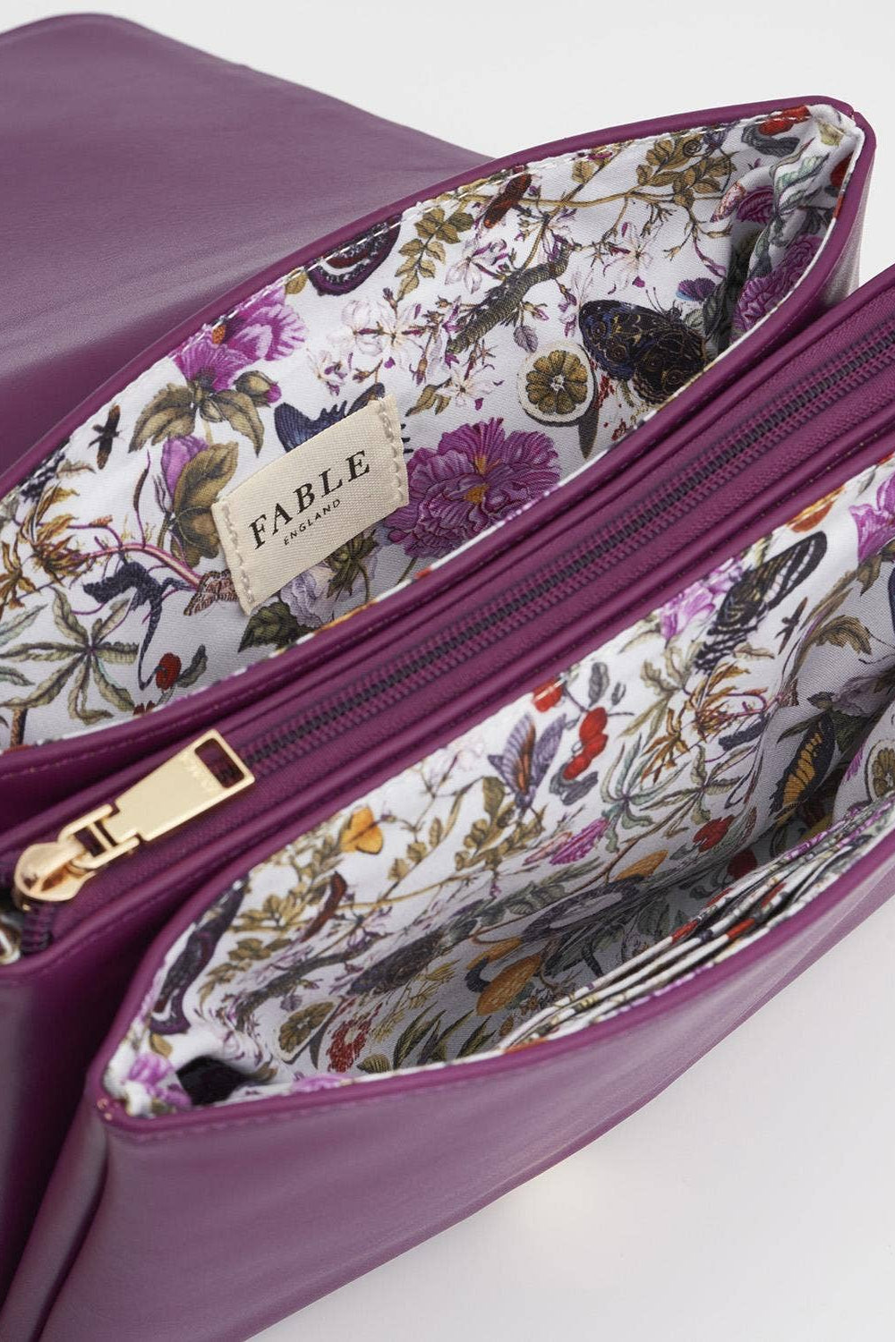Purple handbag with floral interior and 'Fable' brand label on a white background