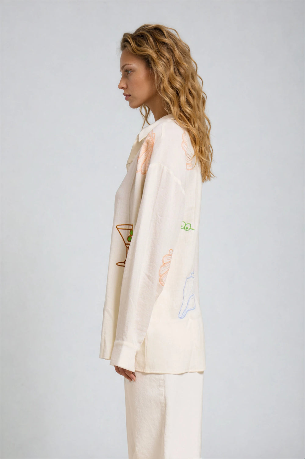 Woman wearing a beige suit with embroidered designs on a white background