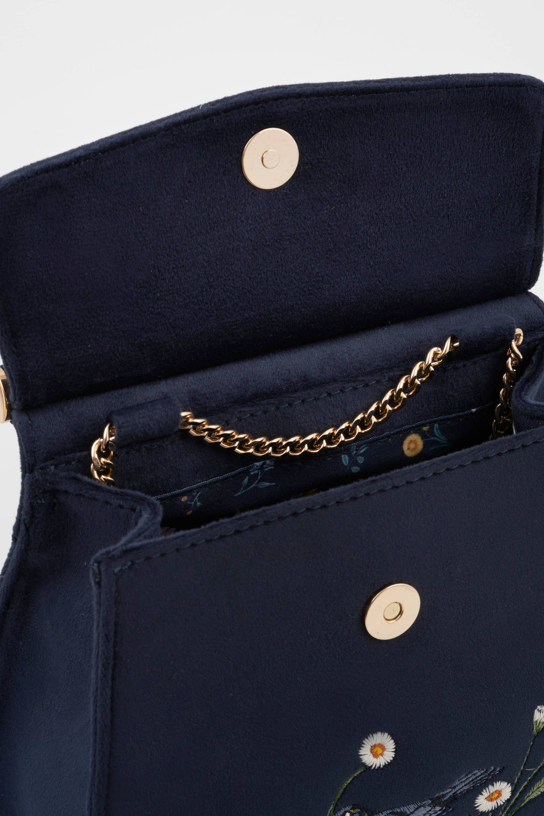Navy blue handbag with gold chain and floral embroidery on a light gray background