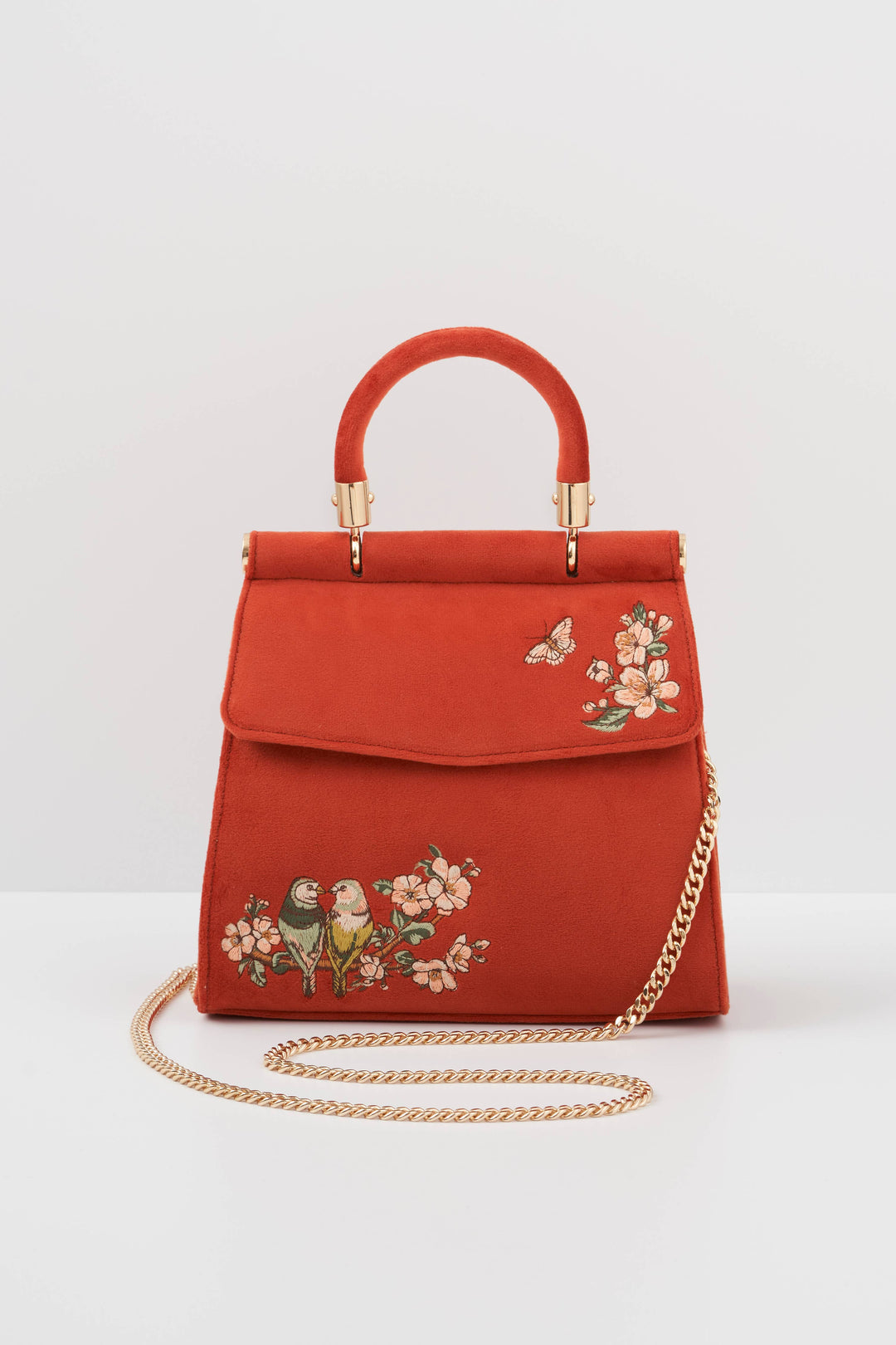 Red handbag with floral embroidery and gold chain on a white background