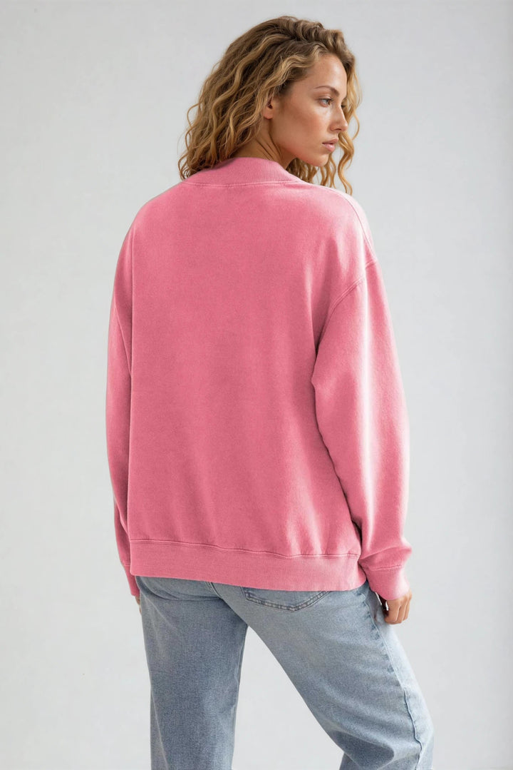 Person wearing a pink sweatshirt and light blue jeans on a plain background