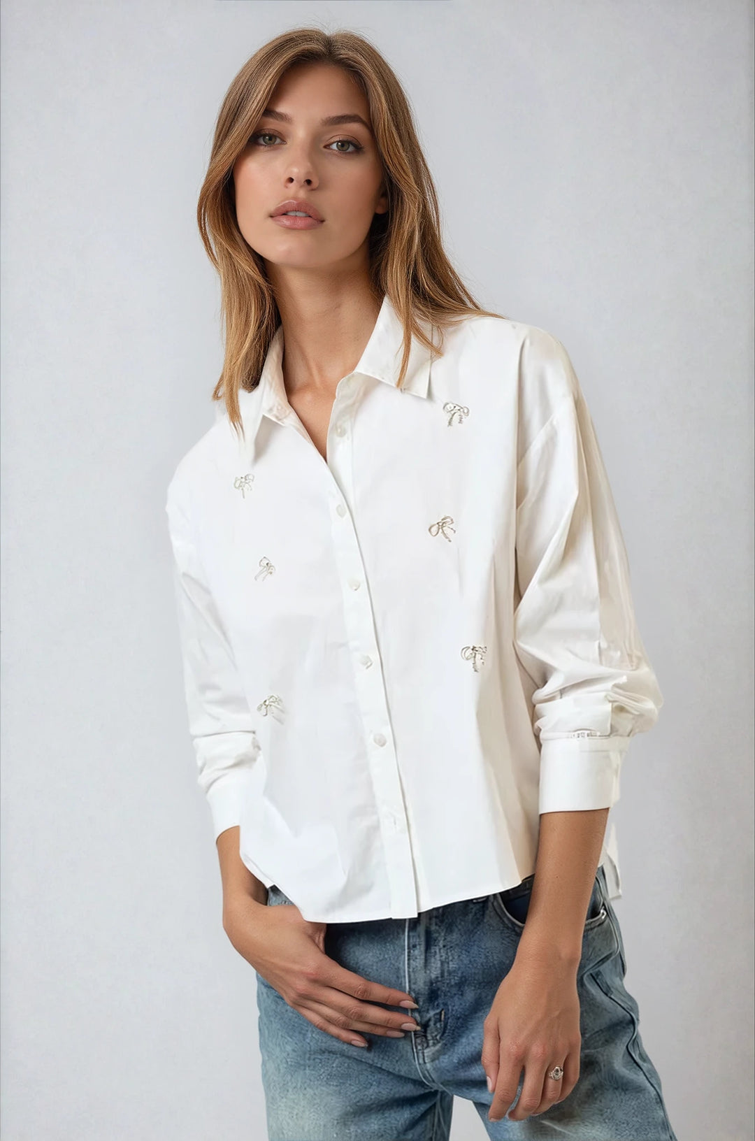 Off white button down shirt with rhinestone bow accents on model