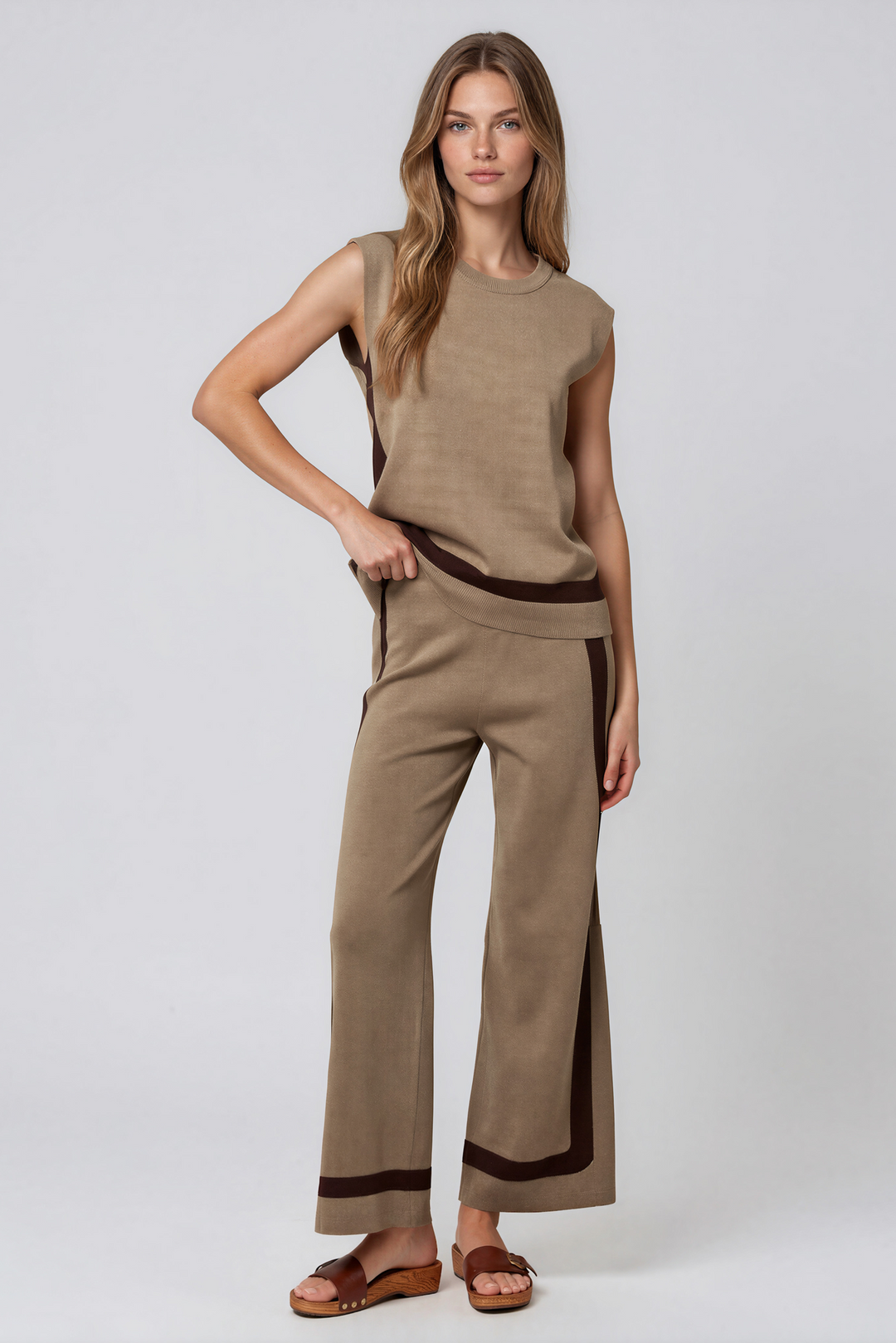 Woman wearing taupe knit sleeveless top and matching wide-leg pants set with contrast brown stripe detail